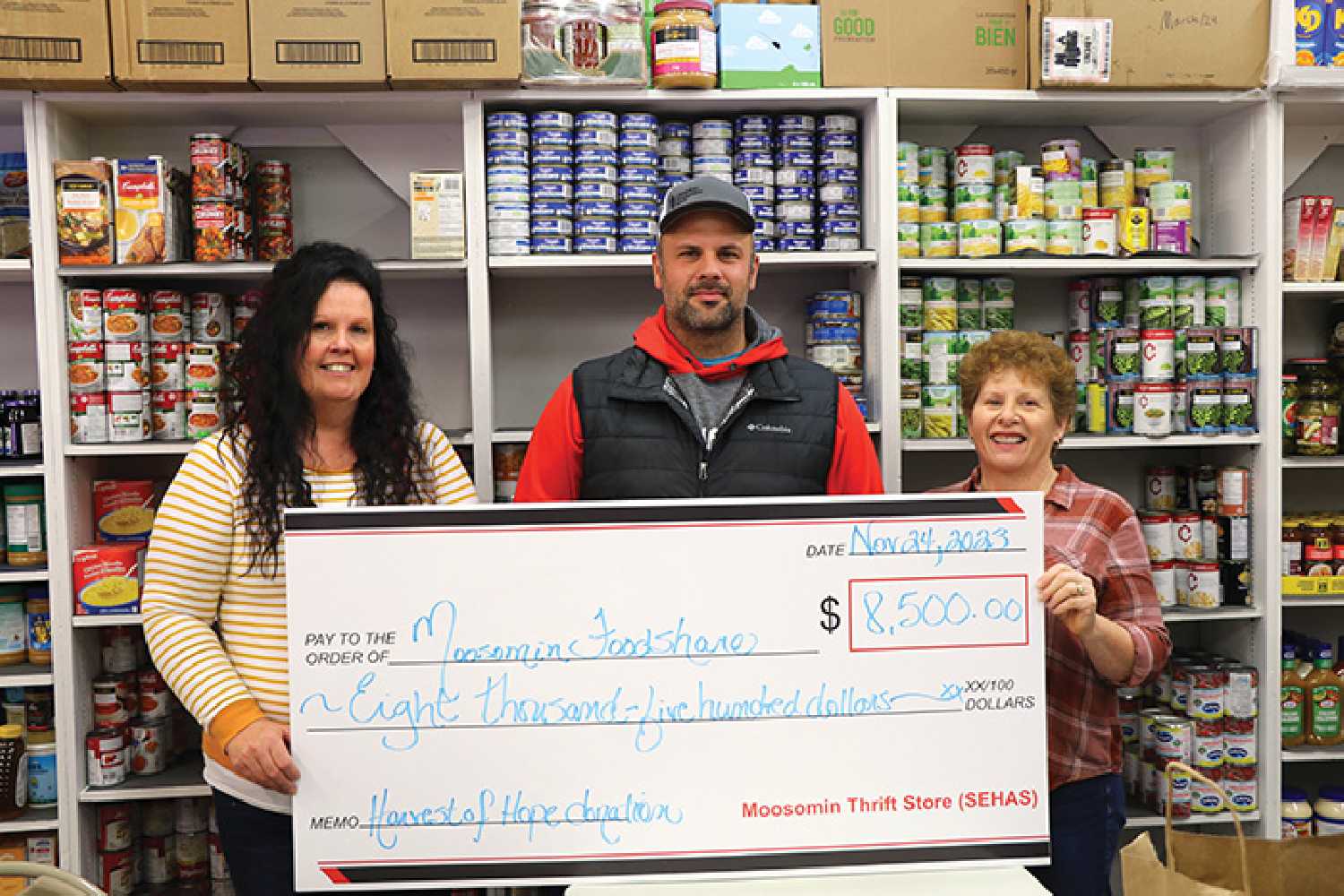 Marguerite Osborne, at left, and Lori Shepherd, at right, with the Moosomin Food Share, accepting a cheque for $8,500 from Kyle Penner of Harvest of Hope.